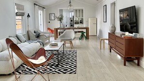 Amplia sala de estar con techo alto, muebles modernos y una cocina al fondo.