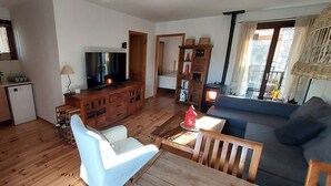 A living room with a TV, wooden furniture, a sofa, and a dining table. - Charming holiday rental apartment in the beautiful Pyrenees of France (Err)