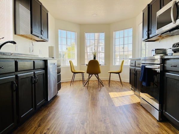 A modern kitchen with black cabinets, stainless steel appliances, and a wooden floor.