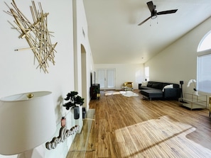 A spacious living room with a wooden floor, a ceiling fan, a sofa, and a coffee table.