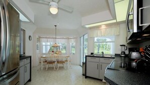 A kitchen with a dining area, a ceiling fan, and a window with curtains. - Single family pool home in a quiet neighborhood, close to five beaches,  (Port Charlotte)