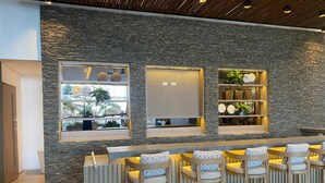 Een moderne bar met stenen muren, barstoelen en planken met decoratieve objecten.