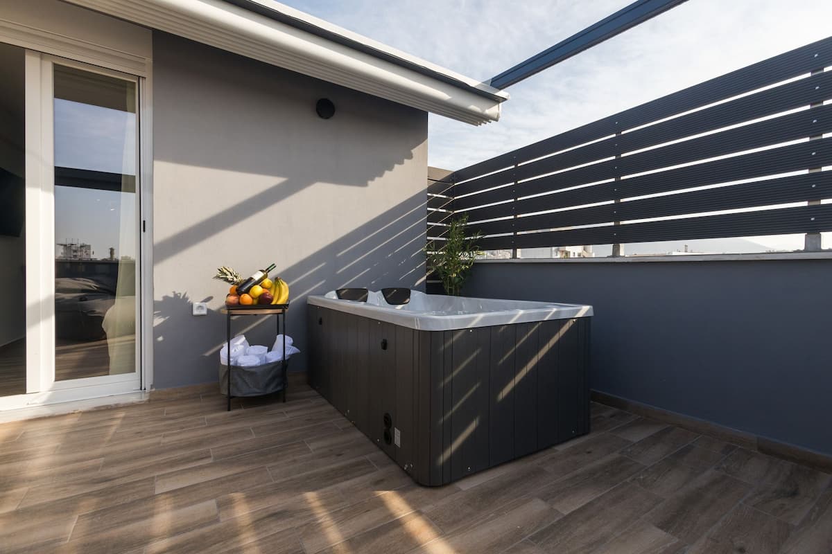 Un balcon moderne doté d’un jacuzzi, d’un plancher en bois et offrant une vue sur la ville.