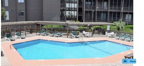 A rectangular pool with a tiled deck, surrounded by lounge chairs and umbrellas. - Amazing Ocean and Pool Views!  Unit 211 - BEAUTIFUL POOL DECK REMODEL COMPLETE! (North Myrtle Beach)