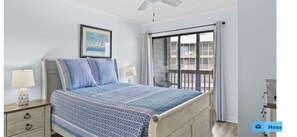A bedroom with a bed, two bedside lamps, a framed picture, and a window with a view of a building. - Amazing Ocean and Pool Views!  Unit 211 - BEAUTIFUL POOL DECK REMODEL COMPLETE! (North Myrtle Beach)