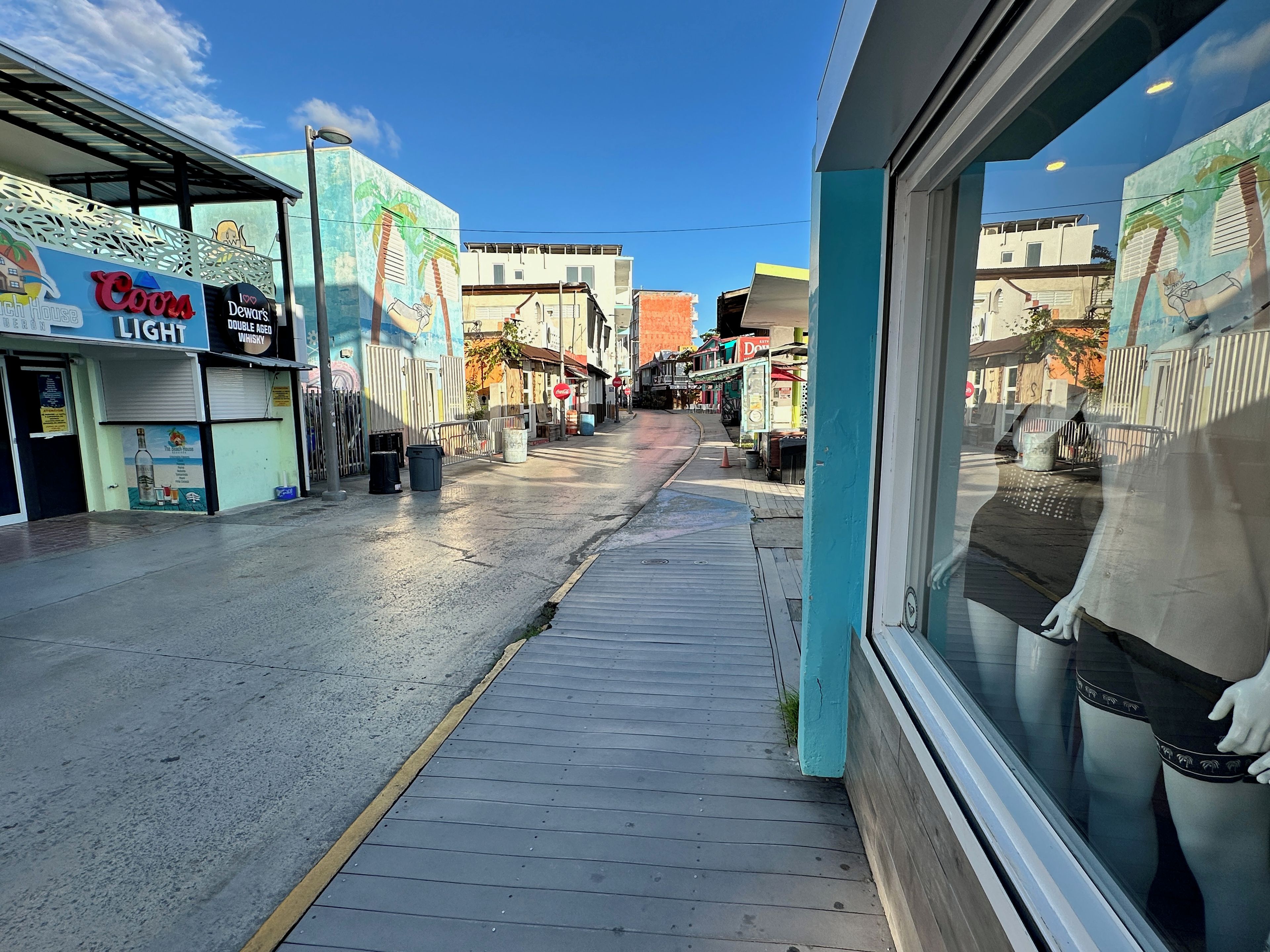 A street with storefronts, including a visible sign for 'Cora Light Double Aged Whisky'.