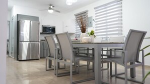 Eine moderne Küche mit einem Edelstahl-Kühlschrank, einem Esstisch mit vier Stühlen und einem Deckenventilator.