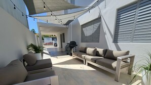 Eine Terrasse im Freien mit einer Couch, einem Grill und Lichterketten.