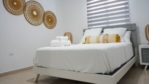 Ein modernes Schlafzimmer mit Bett, weißer Bettwäsche und Wandkunst.