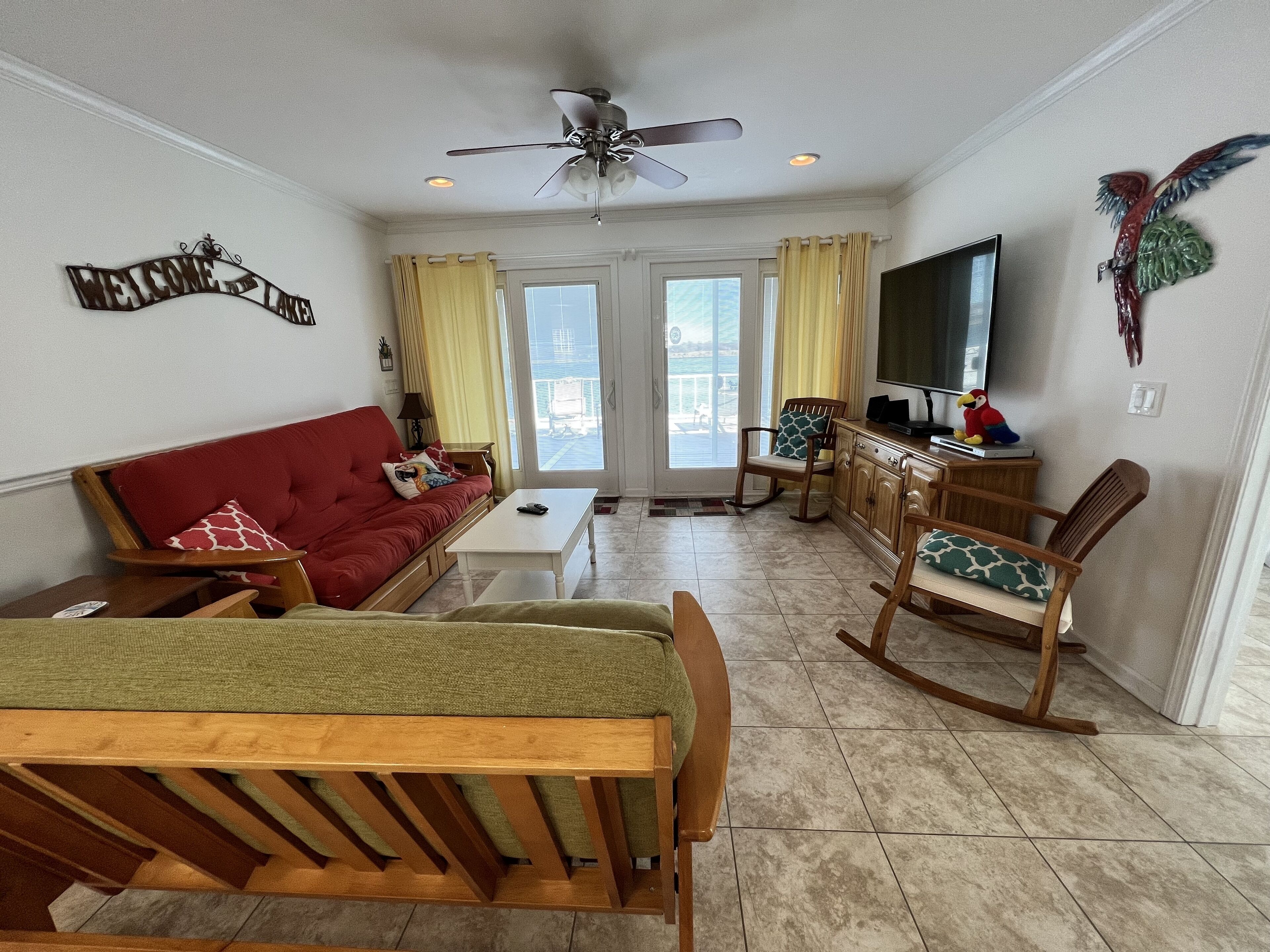 A living room with a red sofa, a wooden dining table, a TV, and a ceiling fan.