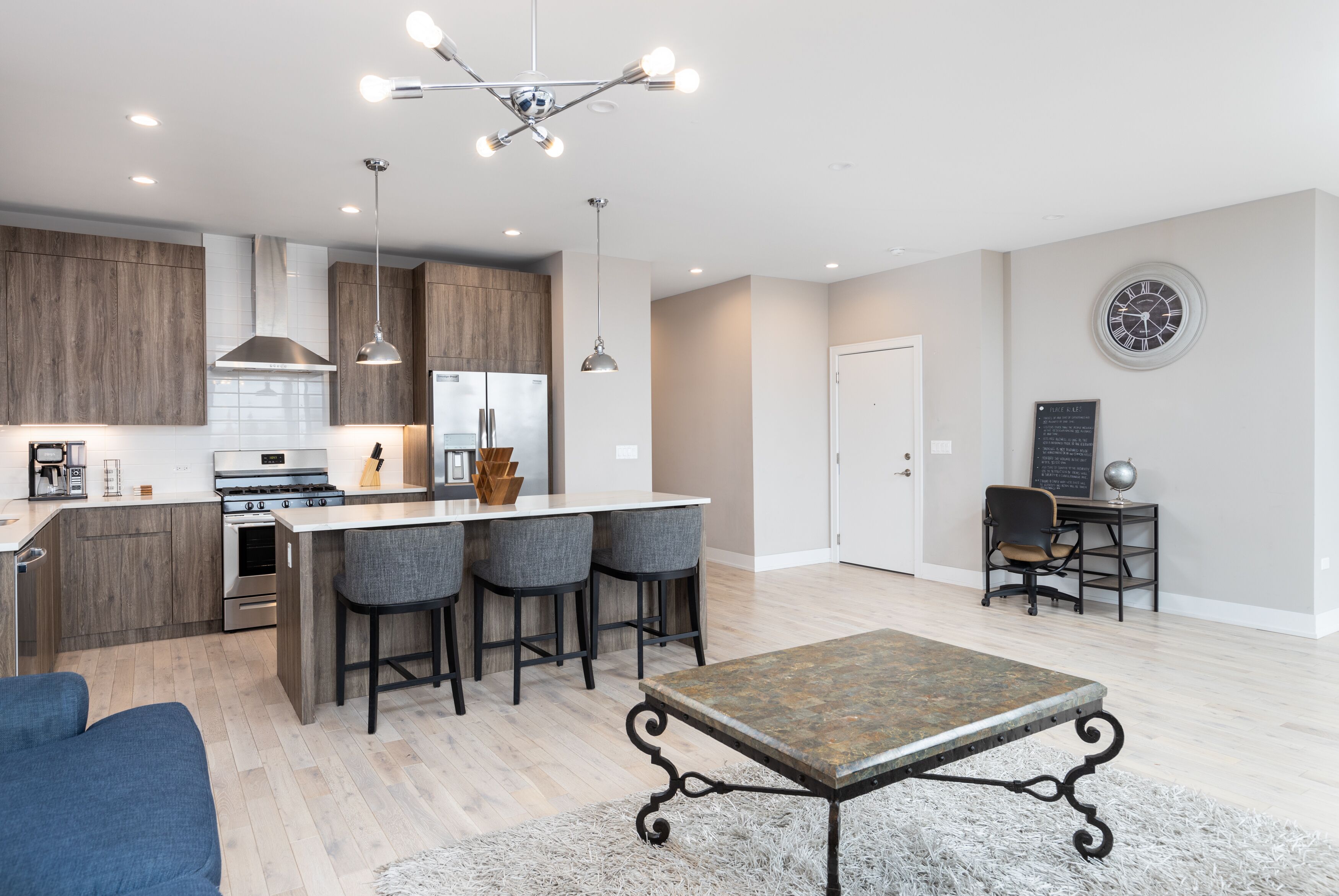 A modern kitchen with a central island, bar stools, and pendant lighting.