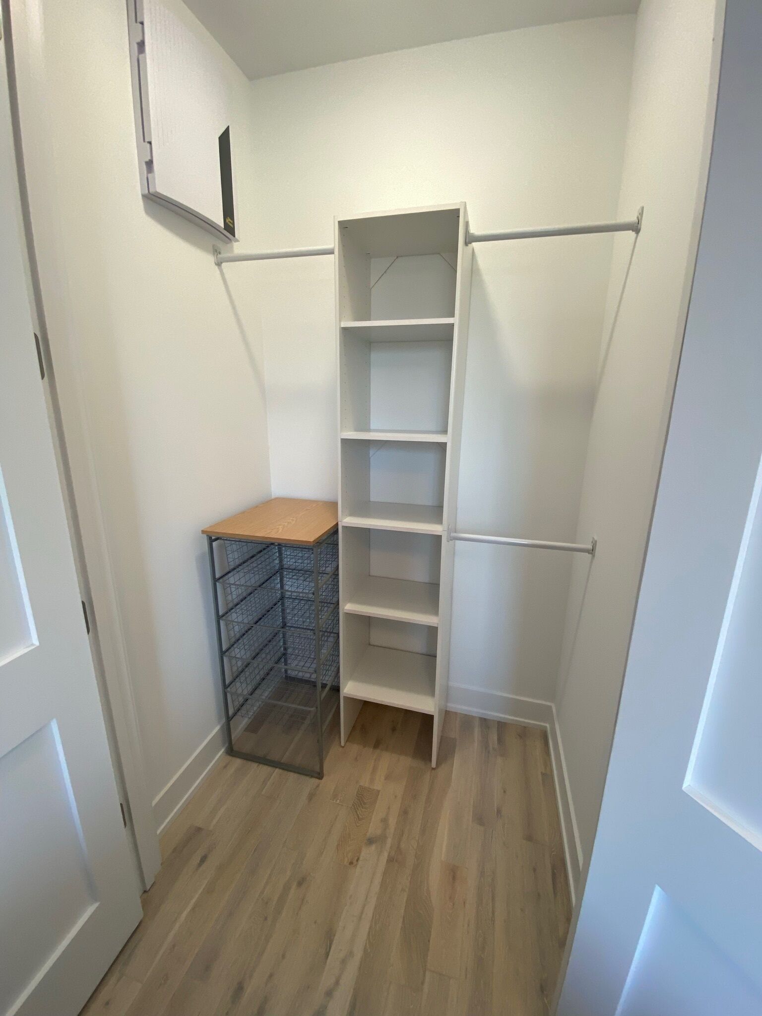 Un dressing avec une étagère métallique et une étagère blanche.