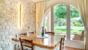 A dining area with a stone wall, a wooden table, and chairs. There is a bottle of wine on the table. - Stunning home in Fanzolo di Vedelago (Fanzolo di Vedelago)