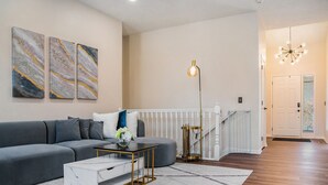 A modern living room with a grey sofa, a white coffee table, and marble artwork on the wall.