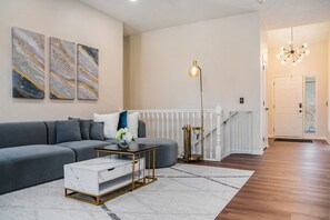 Una sala de estar moderna con un sofá gris, una mesa de centro blanca y una obra de arte de mármol en la pared.