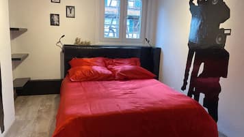A bedroom with a bed, a window, and a wall with a large abstract painting.