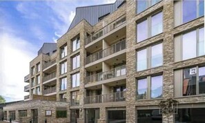 Residential building with modern design, featuring large windows and balconies with outdoor access.