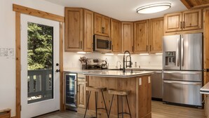 A modern kitchen with wooden cabinets, stainless steel appliances, and a large island with bar stools. - Luxury Vail 3bd/2ba w/ Hot Tub! (Vail)