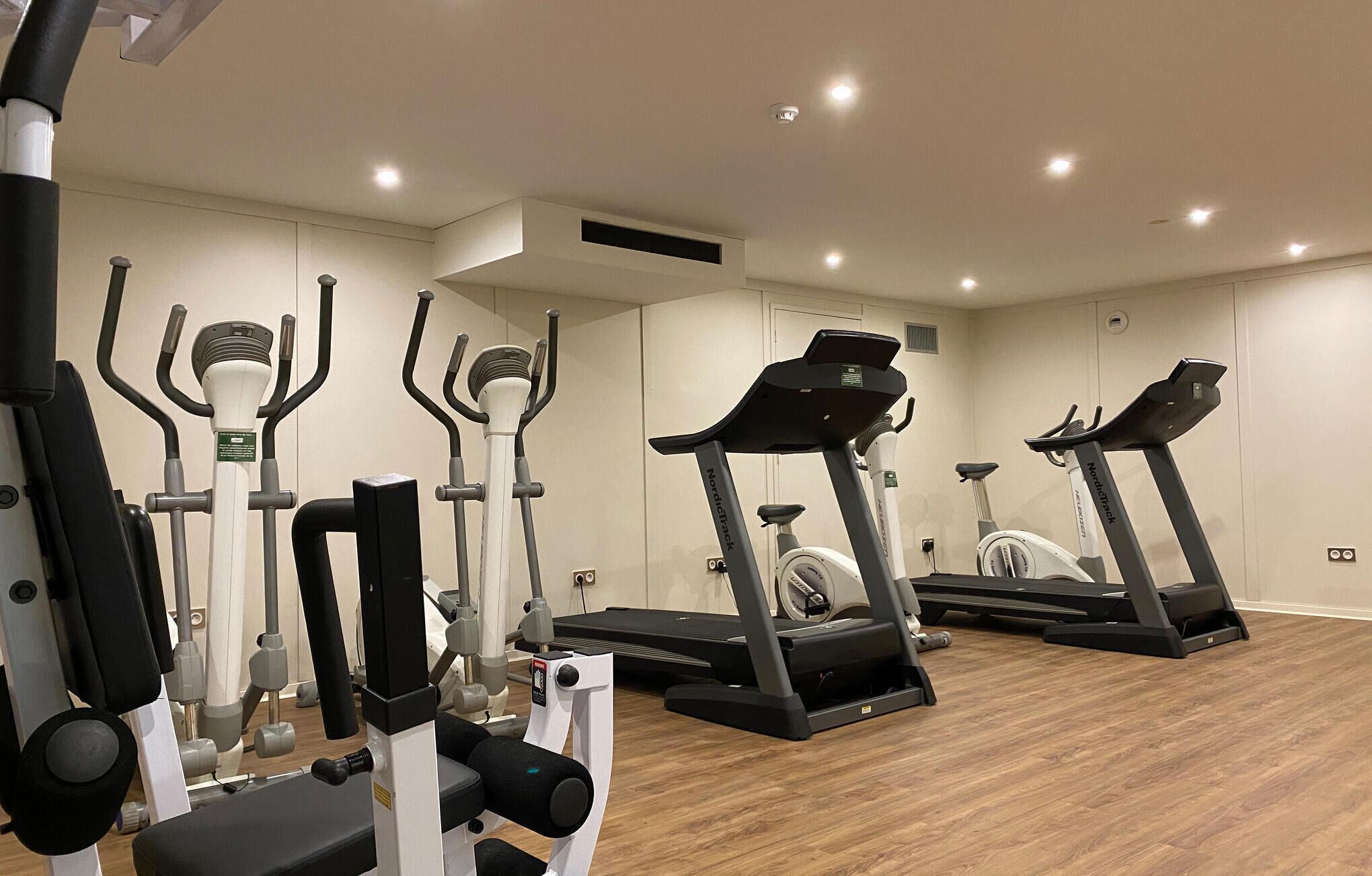 Une salle de sport équipée de tapis de course, de vélos elliptiques et d’appareils de musculation.
