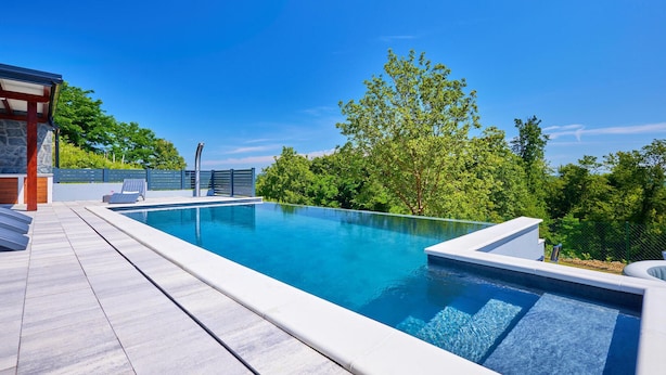 A modern outdoor swimming pool with a stone deck, lounge chairs, and a view of lush greenery. - Nice home in Bedenica (Bedenica)