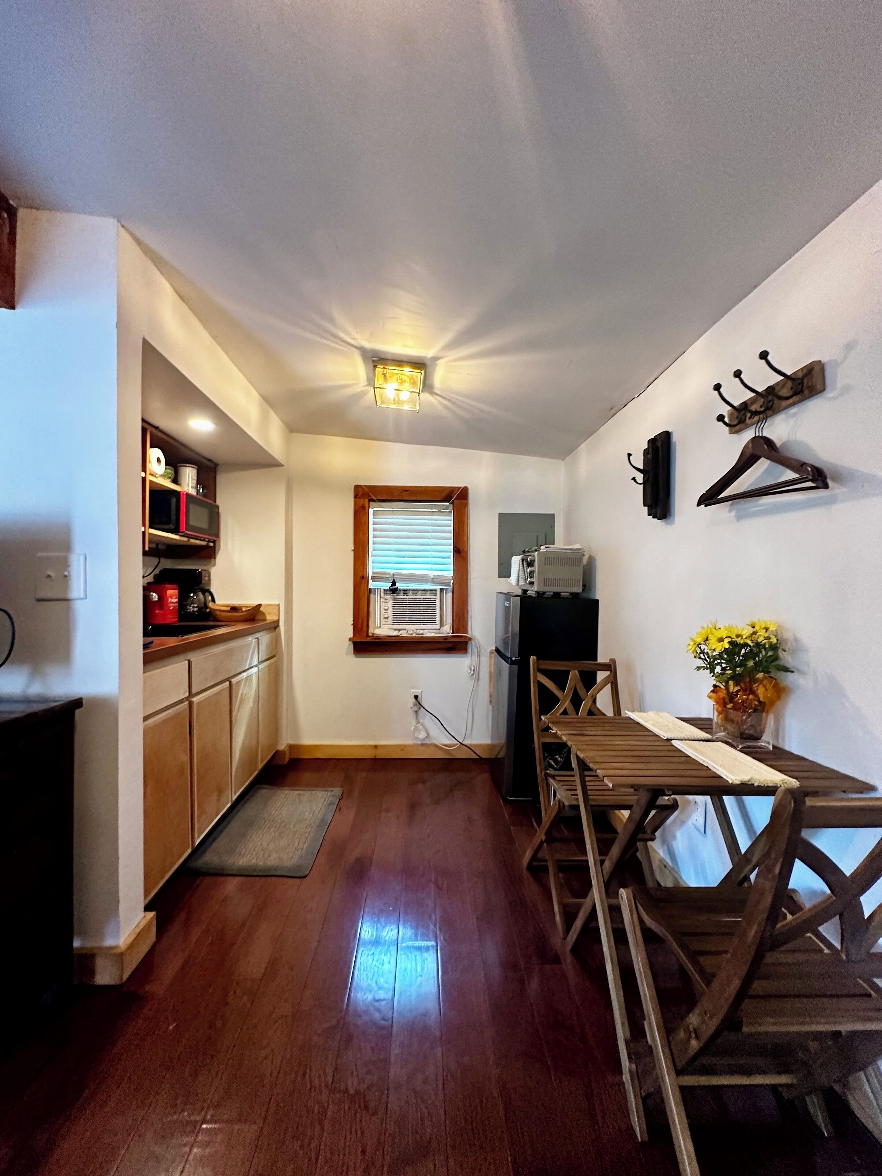 A compact kitchen with wooden cabinets, a microwave, and a small dining area with a table and chairs.