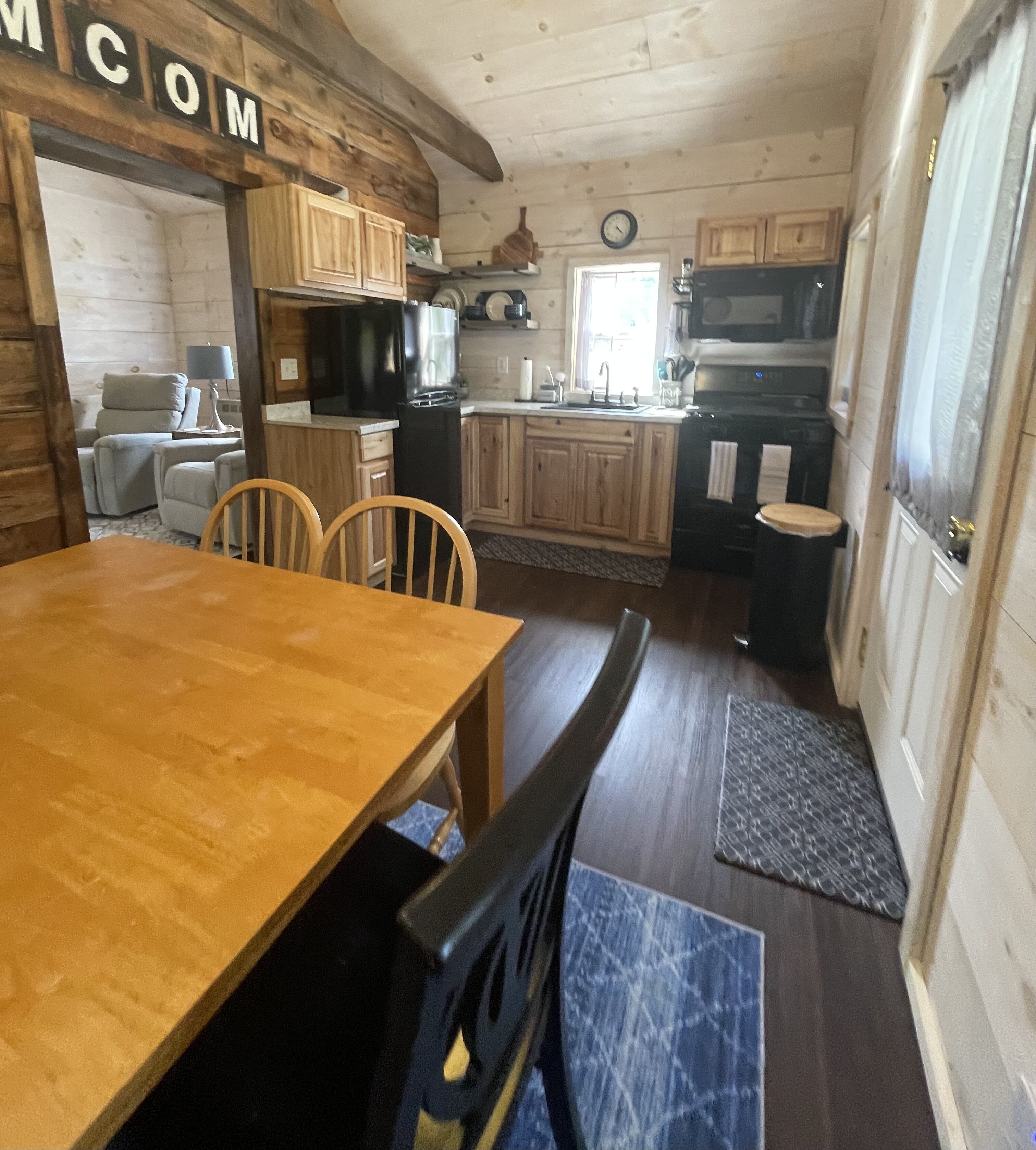 Une cuisine de taille réduite avec des meubles en bois, une table à manger et un four à micro-ondes.