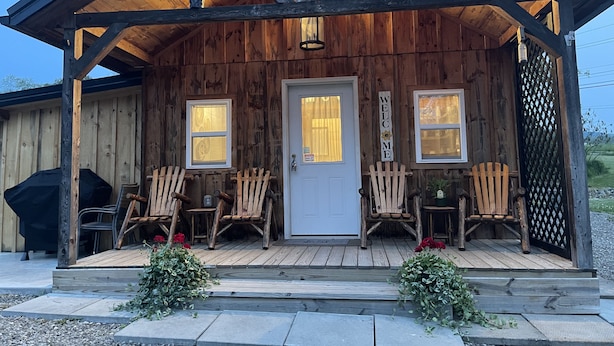 Eine rustikale Holzhütte mit Veranda, zwei Fenstern und einem Willkommensschild.