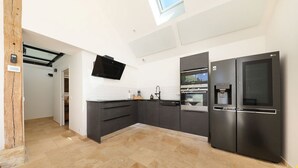 A modern kitchen with dark cabinetry, a built-in oven, a microwave, and a double-door refrigerator.