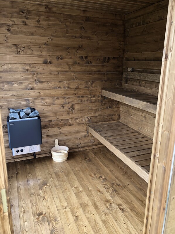 Una cabaña de madera con sauna, calentador de agua y banco de madera.