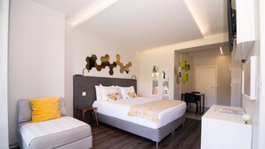 Une chambre d’hôtel moderne équipée d’un lit, d’un canapé, d’un bureau et d’une télévision.