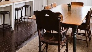 A dining area with a wooden table and chairs, a hanging lantern, and a white door in the background.