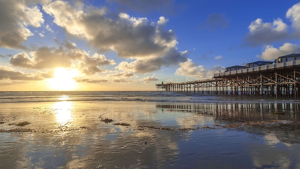 A pier extending into the water with a sunset in the background.
