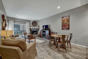 A living room with a fireplace, a dining area with a round table, and a sofa. - Private River Access, Pool, Hot tub, BBQ grill walk downtown & Bahn. Free Tubes! (New Braunfels)