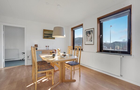 A dining area with a wooden table and chairs, a window with a view, and a radiator on the wall. - Stunning home in Nordborg with kitchen (Nordborg)