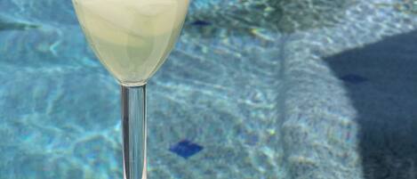 A cocktail glass with ice cubes on a poolside table.