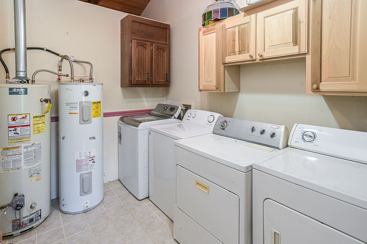 A laundry room with a washer, dryer, and two water heaters.