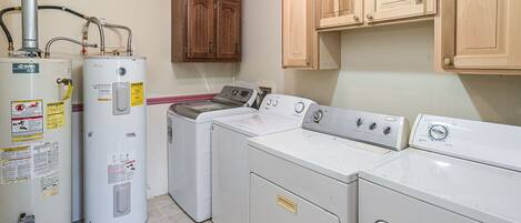 A laundry room with a washer, dryer, and two water heaters.