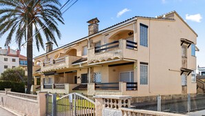 A two-story building with balconies, a gated entrance, and a palm tree in the background. - WELCS APARTAMENTO 218 EMP frente al Mar (Empuriabrava)