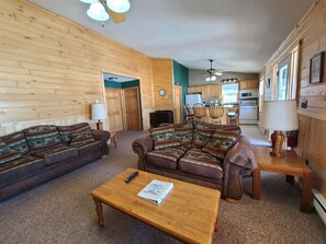 Ein gemütliches Wohnzimmer mit zwei Sofas, einem Holztisch und einer Küche im Hintergrund.