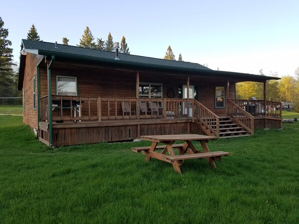 Eine Holzhütte mit Veranda, Picknicktisch und überdachtem Bereich mit Treppe.