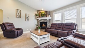 A living room with a stone fireplace, leather sofas, and a coffee table.