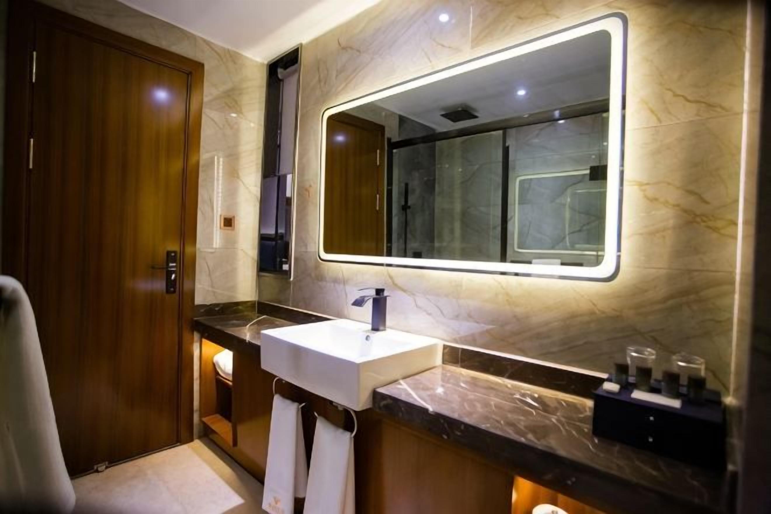A modern bathroom with a marble vanity, a large mirror, and a shower area.