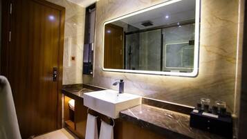 A modern bathroom with a marble vanity, a large mirror, and a shower area.
