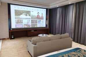 A modern living room with a large flat-screen TV, a sofa, a coffee table, and a dark curtain backdrop. - Jingan Haoting Hotel (Gengma)