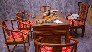 A wooden dining table with chairs, a teapot, cups, and a menu.