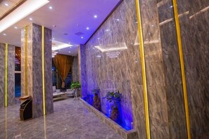A lobby with marble walls, a reception desk, and a seating area. - Jingan Haoting Hotel (Gengma)