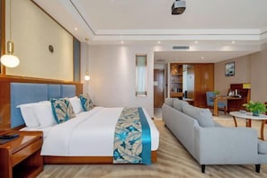 A hotel room with a bed, a sofa, a small table, and a desk. - Jingan Haoting Hotel (Gengma)
