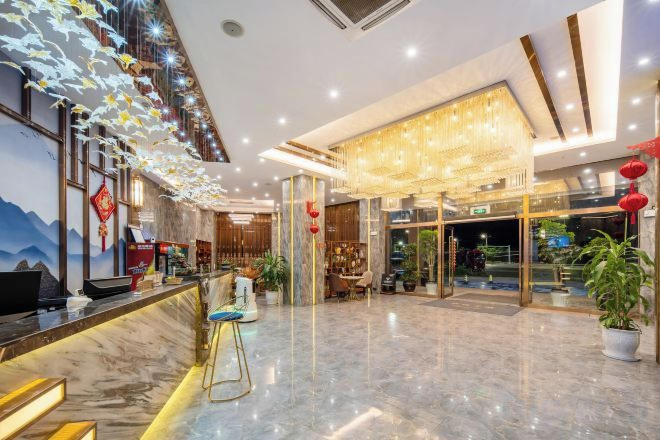 A hotel lobby with a reception desk, seating area, and a large chandelier.
