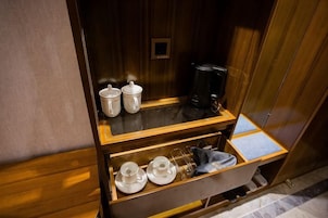 A compact kitchenette with a coffee maker, two cups, and a small sink.