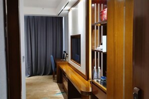 A room with a wooden desk, a television, a bookshelf, and a curtain. - Jingan Haoting Hotel (Gengma)